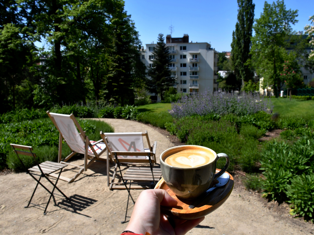 Flat white v hrnečku s výhledem do zahrad Arnoldovy vily.