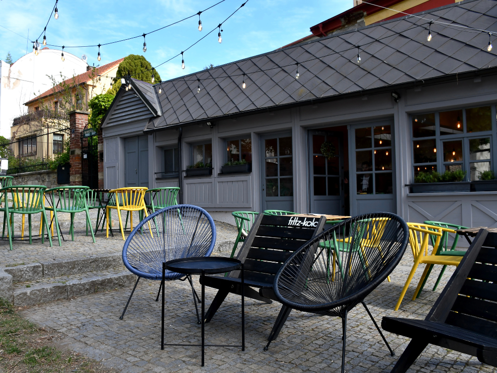 Šedý dřevěný vstup do kavárny Turistka s venkovním posezením před kavárnou.